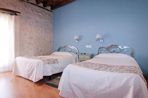 2 camas en una habitación con paredes azules en HOTEL RURAL LOS ABUELOS en Montemayor de Pililla