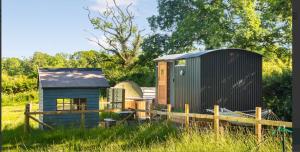 uma pequena casa e um galpão num campo em Shepherds Hut with Scandinavian Hot Tub and hydromassager em Sway