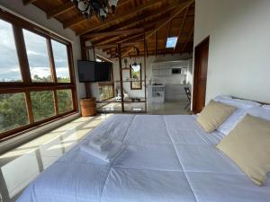 a large white bed in a room with large windows at Glamping Ancestros Ecoparque in Girardota