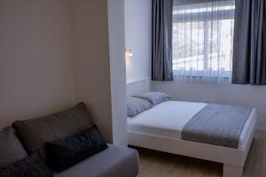 um quarto com uma cama, um sofá e uma janela em Apartments Una em Poljica