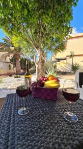 コスタ・カルマにあるHoliday house Fuerteventuraのワイン2杯とフルーツバスケット付きのテーブル