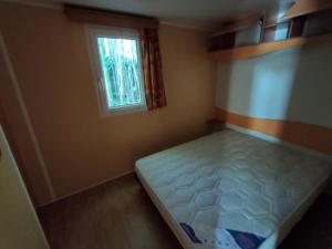 Limogne-en-QuercyCAMPING LE BEL AIR mobil home LE CORNOUILLER 4 personnes的一间有床和窗户的小卧室