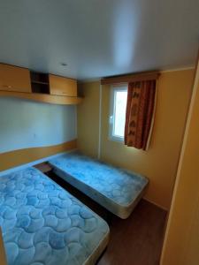 Limogne-en-QuercyCAMPING LE BEL AIR mobil home LE CORNOUILLER 4 personnes的有两张床和一扇窗户的小房间