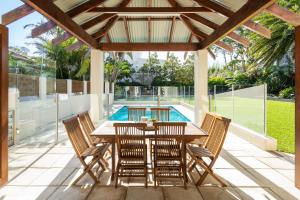 un patio con tavolo, sedie e piscina di Huge Bayside Luxury Resort-Style Home with Pool a Burraneer