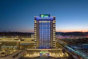 Liaoyuan的住宿－辽源经开区智选假日酒店，一座高大的建筑,上面有蓝色的灯光