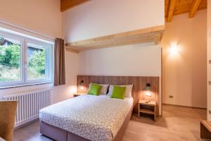 a bedroom with a bed with green pillows and a window at B & B Il Sottobosco in Val Masino