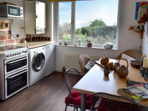una cucina con lavatrice e tavolo con sedie di Pollendor a Falmouth