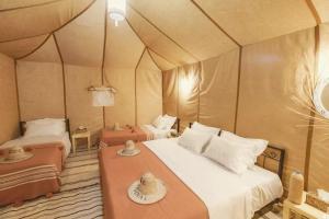 メルズーガにあるMerzouga Luxury Campsのテント内のベッドルーム1室(ベッド2台付)