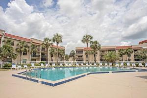 a swimming pool in front of a building with palm trees at Beach Condo Getaway in St. Augustine