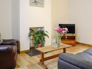 a living room with a couch and a table with flowers at Brodie Cottage in Aspatria