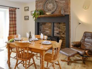 a dining room with a table and chairs and a fireplace at Brodie Cottage in Aspatria