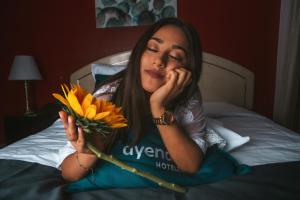 una mujer tendida en una cama sosteniendo un ramo de girasoles en Hotel America Chiclayo en Chiclayo