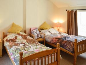 a bedroom with two beds and a window at Brodie Cottage in Aspatria