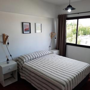 1 dormitorio con 1 cama con edredón a rayas y ventana en Departamento Estudio Alem y San Martin en Mendoza