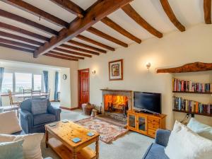 a living room with a fireplace and a tv at Griff Head Cottage in Carlton