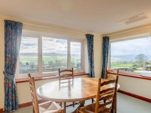 a dining room with a table and chairs and windows at Griff Head Cottage in Carlton