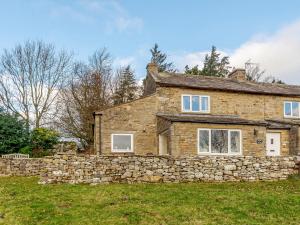 a stone house with a stone wall at Griff Head Cottage in Carlton