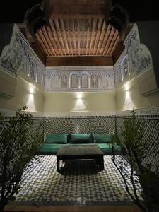 ein Wohnzimmer mit einem grünen Sofa und einer Decke in der Unterkunft Riad D'or meknes in Meknès