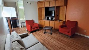 uma sala de estar com um sofá e duas cadeiras e uma televisão em Studios & Suites 4 Less Charlotte em Charlotte