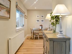 a kitchen and dining room with a table and a lamp at Culbae Cottage in Whauphill