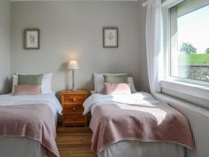 two twin beds in a room with a window at Culbae Cottage in Whauphill