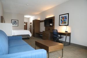 a hotel room with a bed and a couch and a desk at Holiday Inn Express Hotel & Suites Albuquerque Airport by IHG in Albuquerque