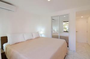 ein weißes Schlafzimmer mit einem Bett und einem Spiegel in der Unterkunft Resort Atlantic Villas & Spa in Punta Cana