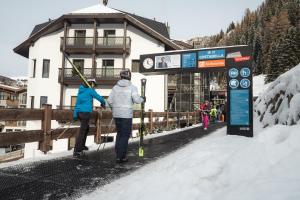 a couple of people with skis at a ski lift at Stella Hotel - My Dolomites Experience in Selva di Val Gardena