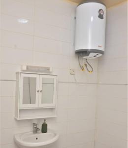 baño con lavabo y armario blanco en Maison d'Hôtes entière Cité Douane Golf Dakar, en Dakar