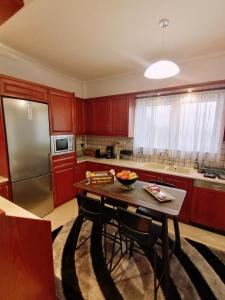 a kitchen with red cabinets and a table and a refrigerator at Thira Apartment near Athens Airport in Spata
