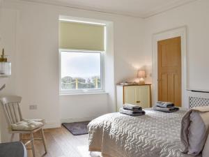 a white bedroom with a bed and a window at Loanmhor in Kilmory