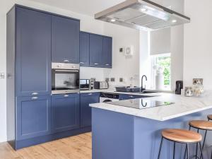 a kitchen with blue cabinets and a white counter top at The Wee White Cottage in Bannockburn
