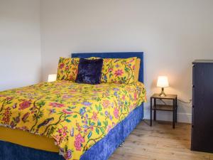 a bedroom with a bed with a colorful bedspread at The Wee White Cottage in Bannockburn