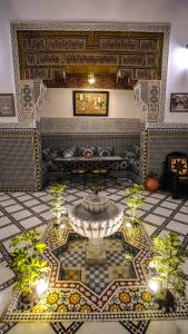 a room with a fountain in the middle of a tile floor at Riad Green House in Fez
