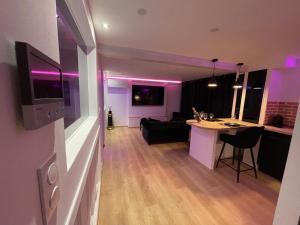 a living room with a kitchen and a living room with purple lights at Le Jacuzzi in Rouen