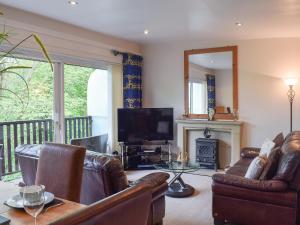a living room with leather furniture and a fireplace at Treetops in Bowness-on-Windermere