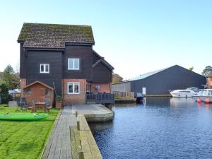 a house on the water with a dock and boats at Davids Island in Wroxham