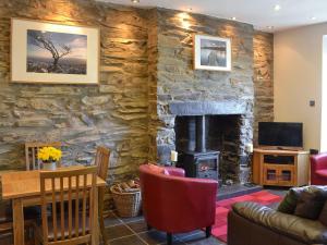 a living room with a stone wall with a fireplace at Gwyrfai Cottage in Waenfawr