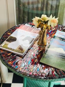 a glass table with books and a vase with flowers at Ibiza Casa in Kent