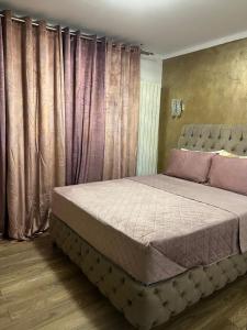 a bedroom with a large bed with purple curtains at Sarah Relax 1 in Drobeta-Turnu Severin