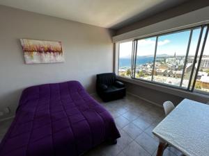 1 dormitorio con cama morada, silla y ventana en seeblickcenter en San Carlos de Bariloche