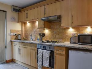 a kitchen with wooden cabinets and a stove top oven at Lily Cottage - Uk40101 in Dunvant