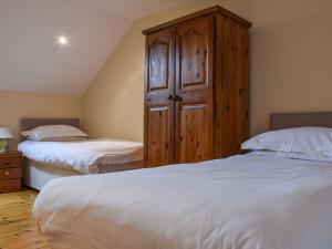 a bedroom with two beds and a wooden cabinet at Lily Cottage - Uk40101 in Dunvant