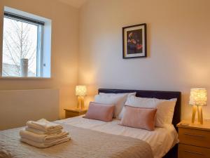 ein Schlafzimmer mit einem Bett mit zwei Lampen und einem Fenster in der Unterkunft Chestnut Lodge in Somerford Keynes