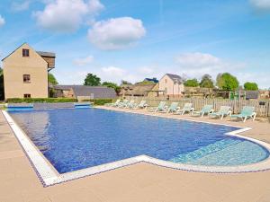 a swimming pool with lounge chairs and a house at Chestnut Lodge in Somerford Keynes