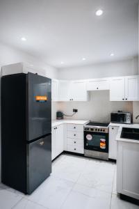 eine Küche mit einem schwarzen Kühlschrank und weißen Schränken in der Unterkunft Najma's villa in Stone Town