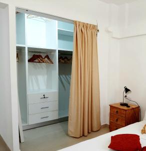 Quiet, colourful home in Cyclades في Konizopí: غرفة نوم مع خزانة مع ستارة بجانب سرير