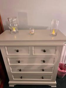 a white dresser with two vases and candles on it at Annie Dee’s Guest Accommodation in Ballygowan