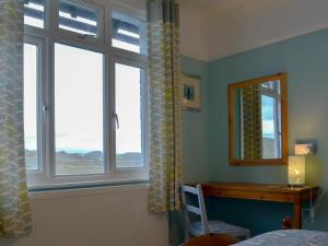a bedroom with two windows and a desk and a bed at Avoca in Looe