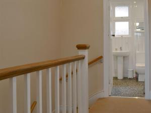 a hallway with a staircase and a bathroom with a toilet at Avoca in Looe